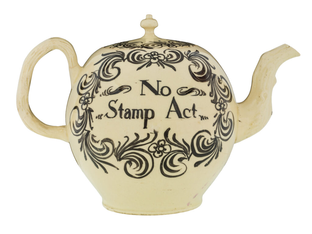 cream-colored teapot with the words "No Stamp Act" and brown leafy scroll work around them